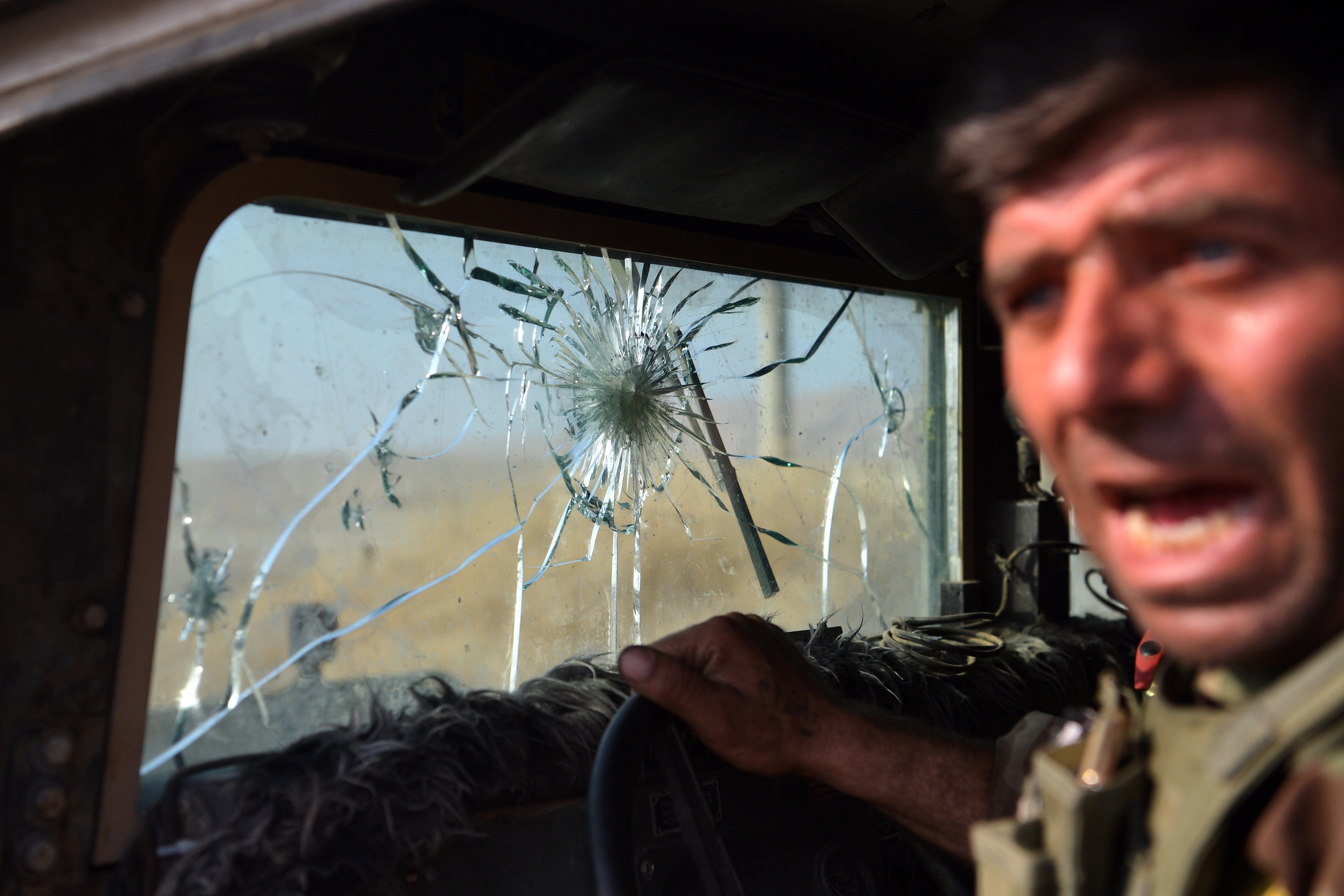 A Kurdish Peshmerga fighter leans out of his military vehicle, which has taken several direct hits from ISIS snipers in the small town of Bartella near Mosul on Oct. 18.