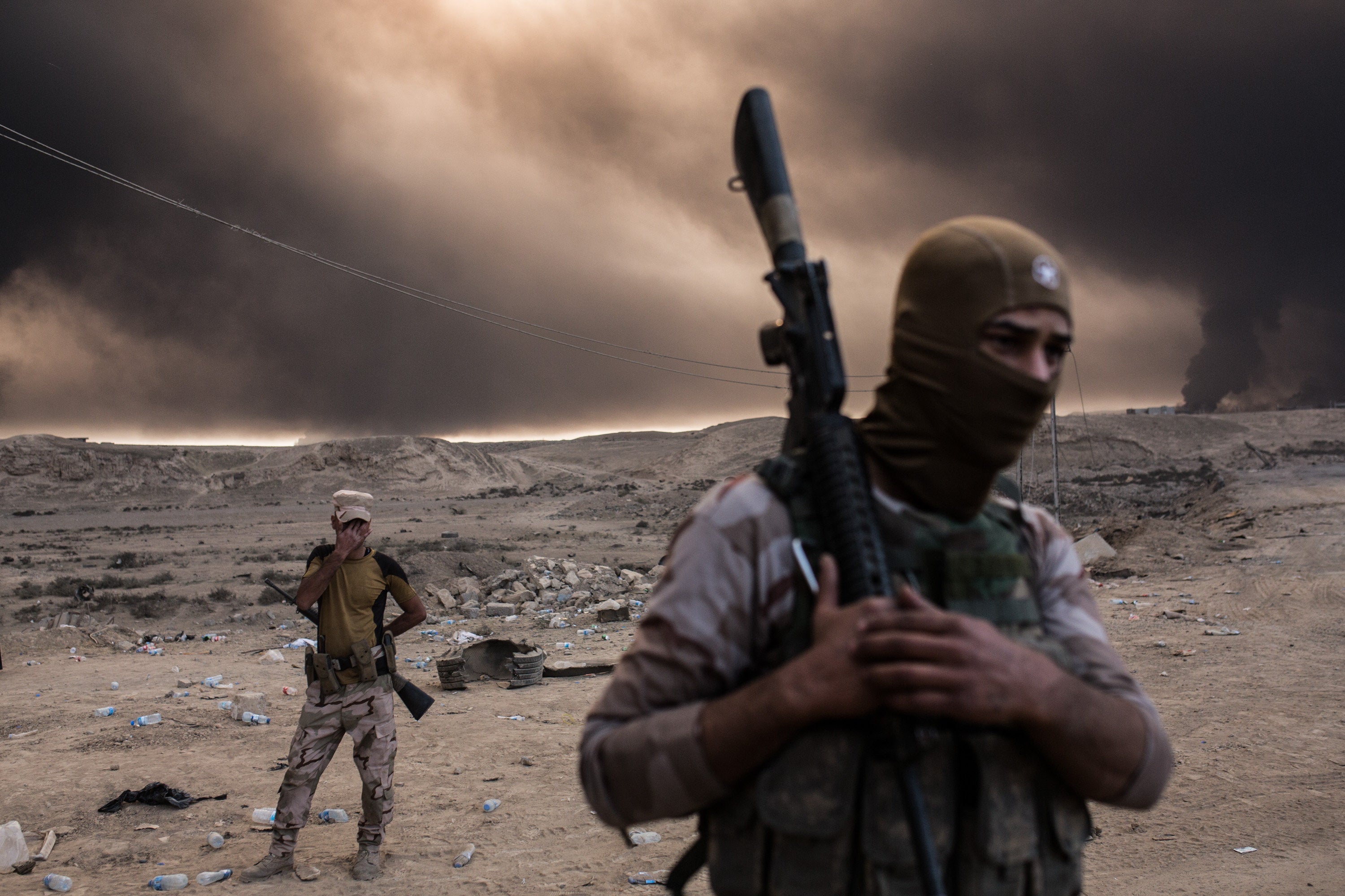 Iraqi soldiers look on as smoke rises from the Qayyarah area, some 35 miles south of Mosul, Iraq, on Oct. 19, 2016.