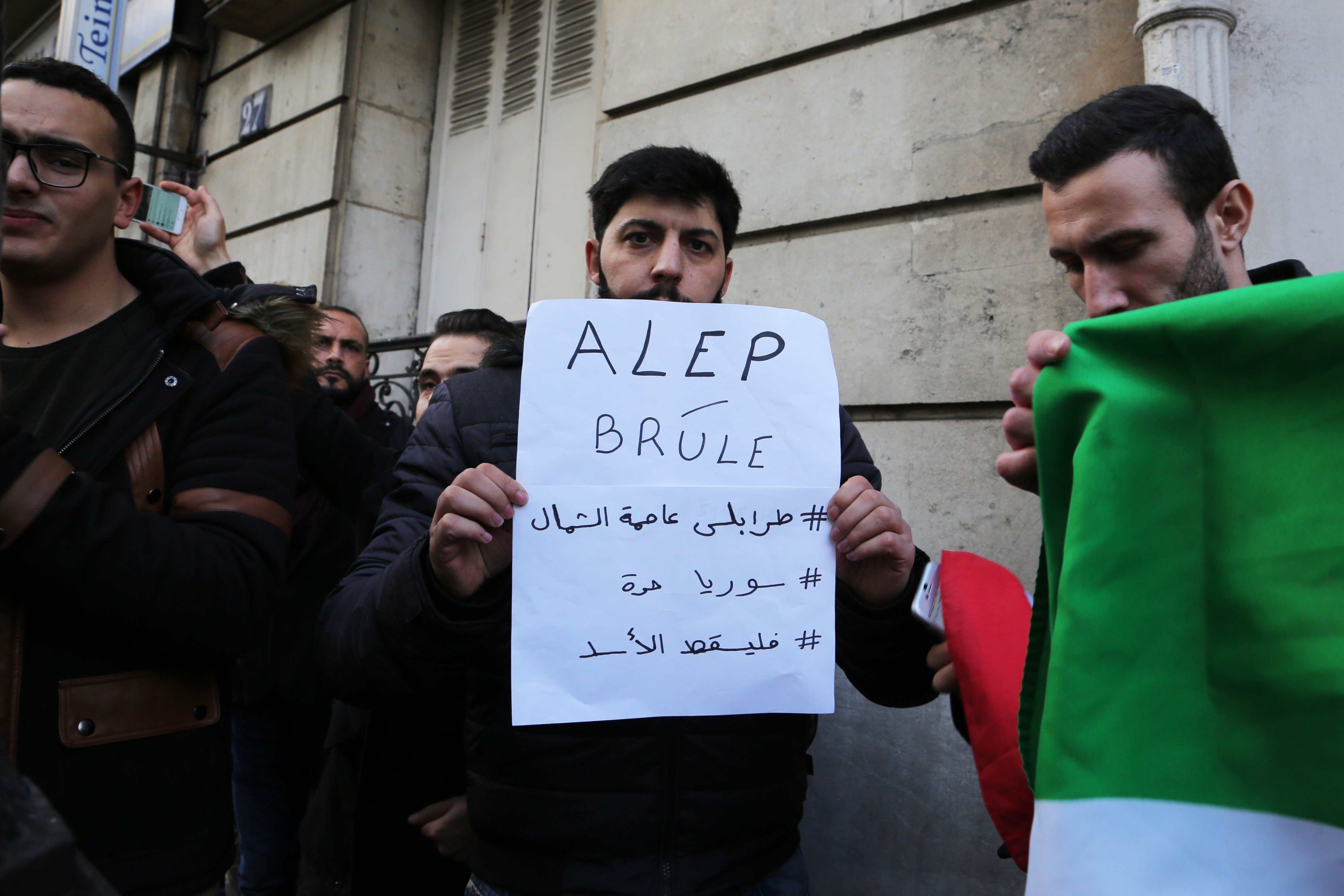 "Aleppo is burning," another man's sign read at the Paris protest.