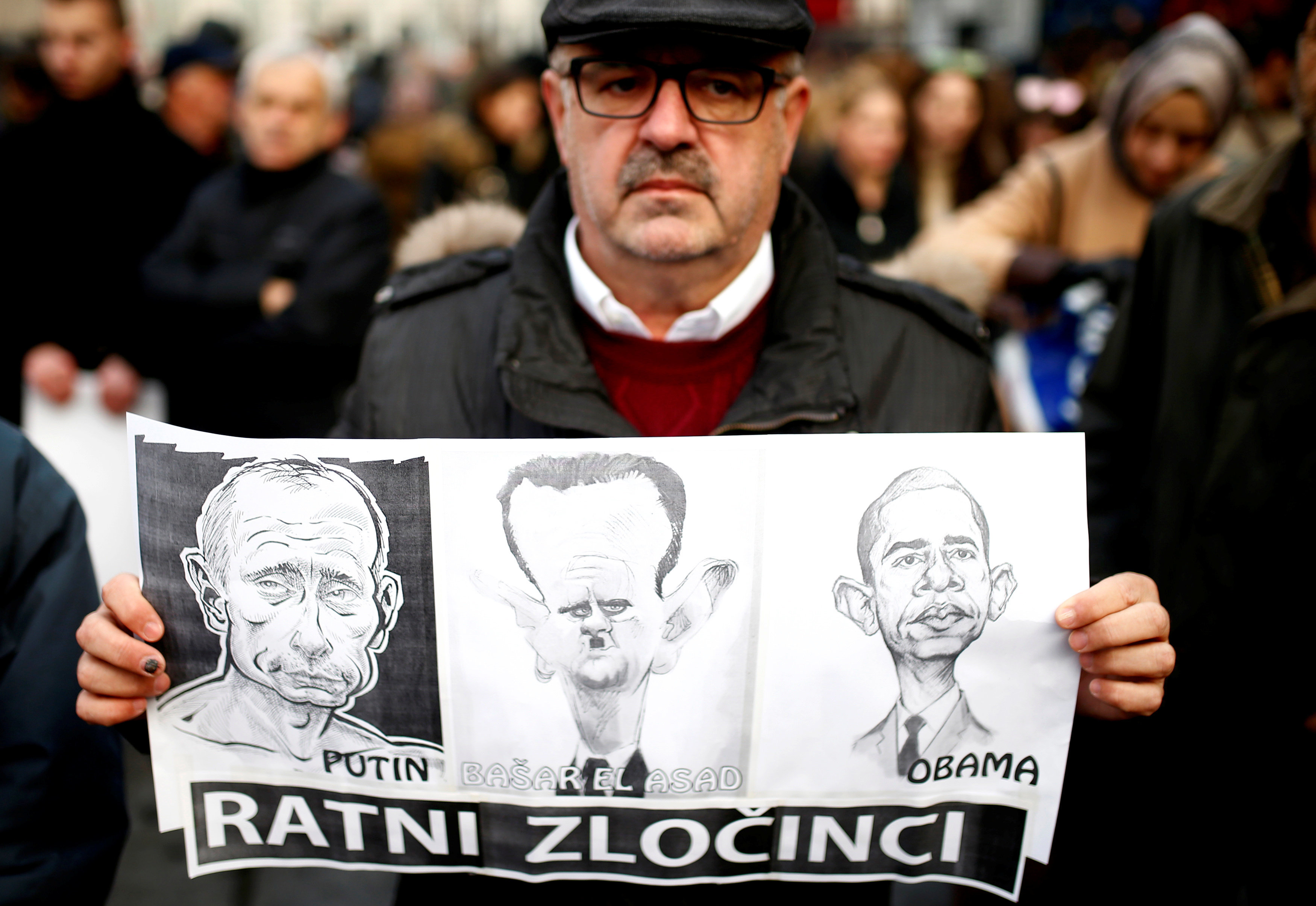 A man holds a placard with caricatures of Russian President Vladimir Putin, Syrian President Bashar Assad and U.S. President Barack Obama in Sarajevo on Dec. 14, 2016.