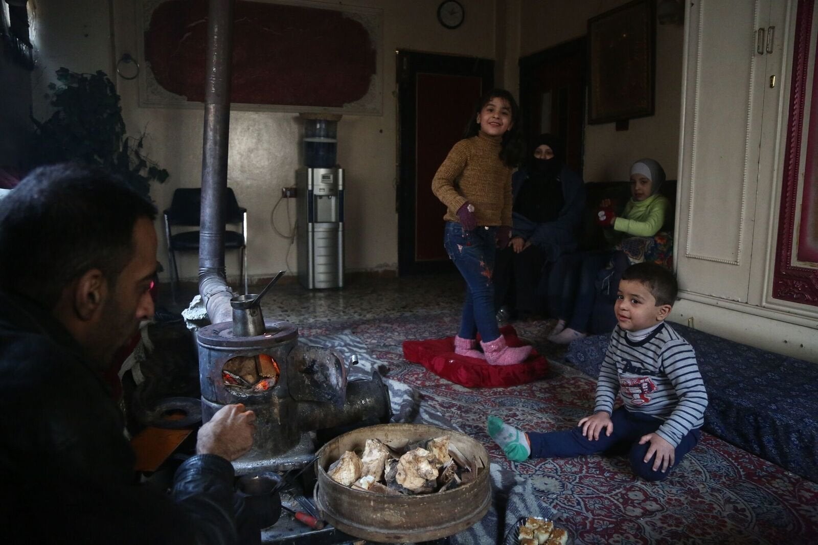 <strong>Engie stands in the living room with her family during a cold winter evening in east Ghouta. She suffers a severe case of haemophilia and needs to receive regular injections that are not available in east Ghouta.</strong>