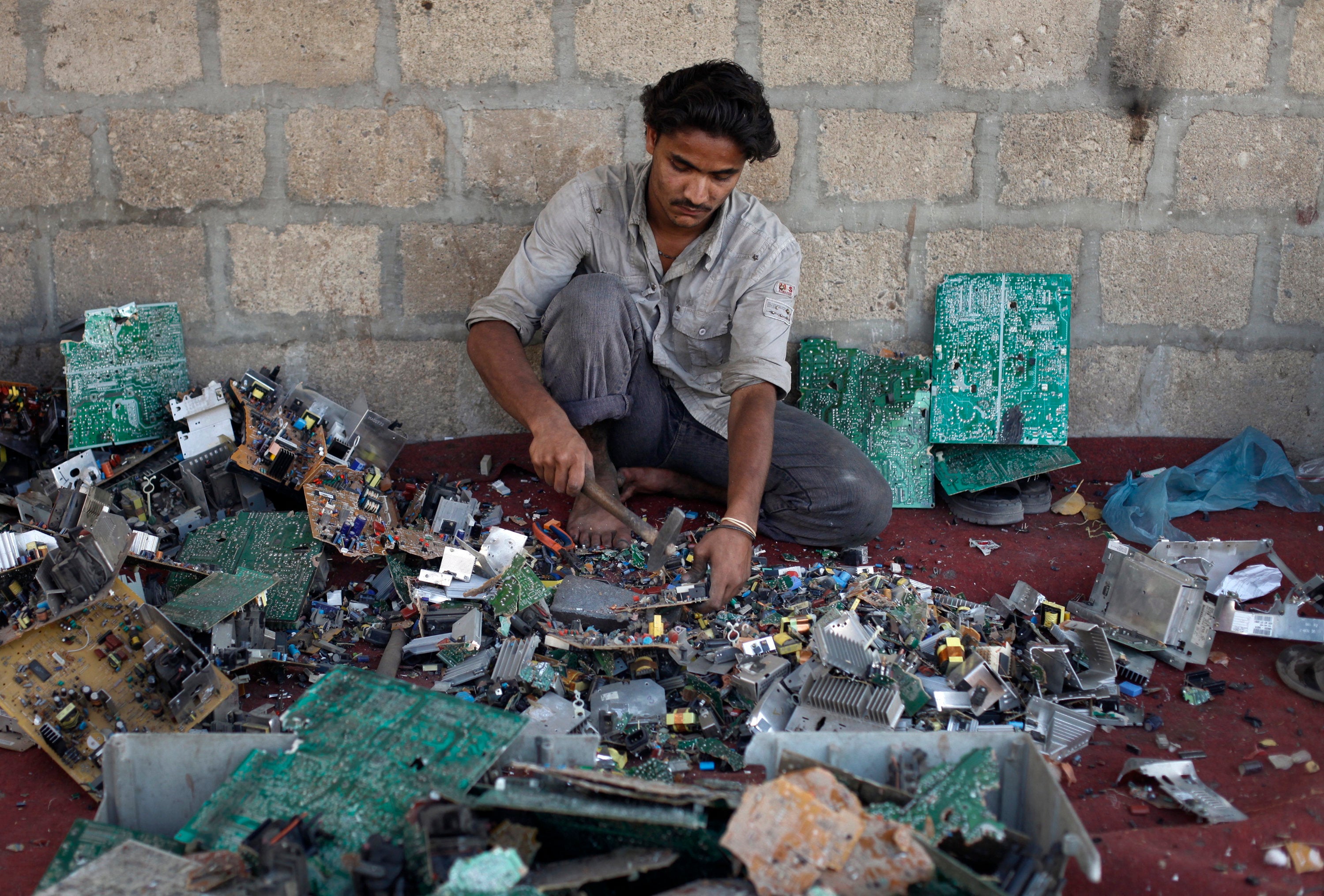 <strong>Ali Raza, 21, a scrap worker breaks apart a computer to retrieve metal in a makeshift workshop in Karachi, Pakistan.</strong>