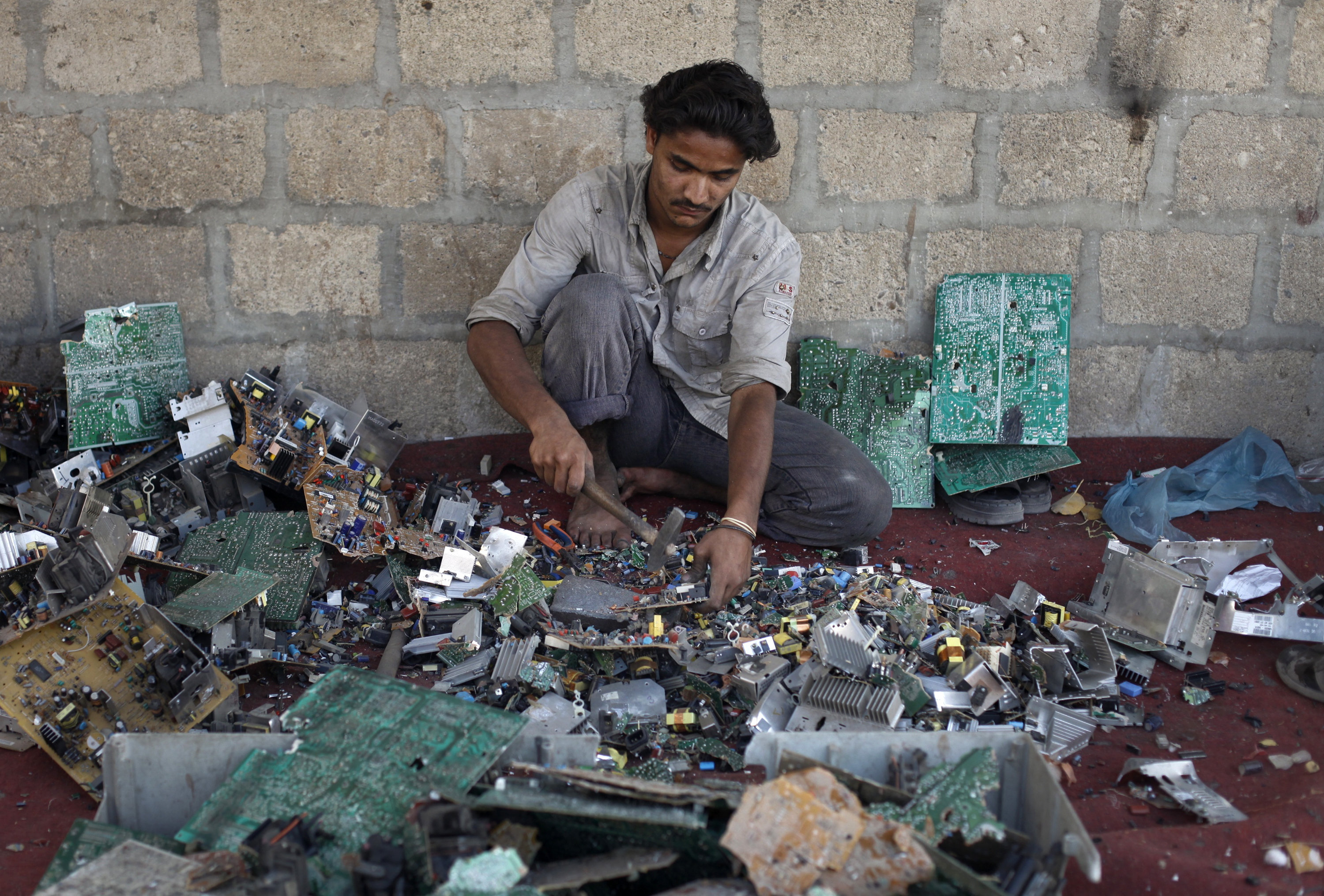 <strong>Ali Raza, 21, a scrap worker breaks apart a computer to retrieve metal in a makeshift workshop in Karachi, Pakistan.</strong>