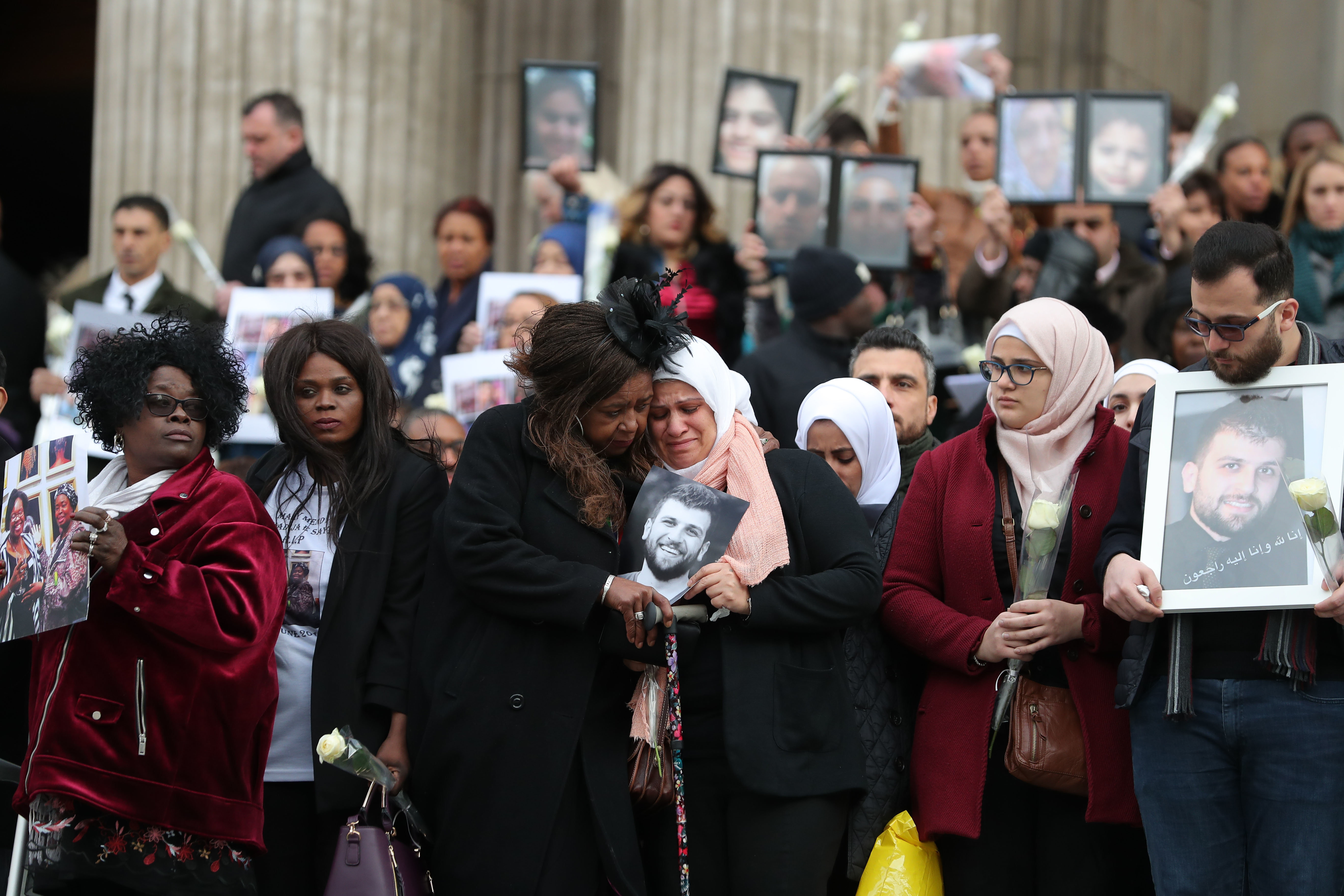 <strong>Mourners&nbsp;hold up pictures of lost loved ones after the Grenfell Memorial Service at St Paul's Cathedral</strong>