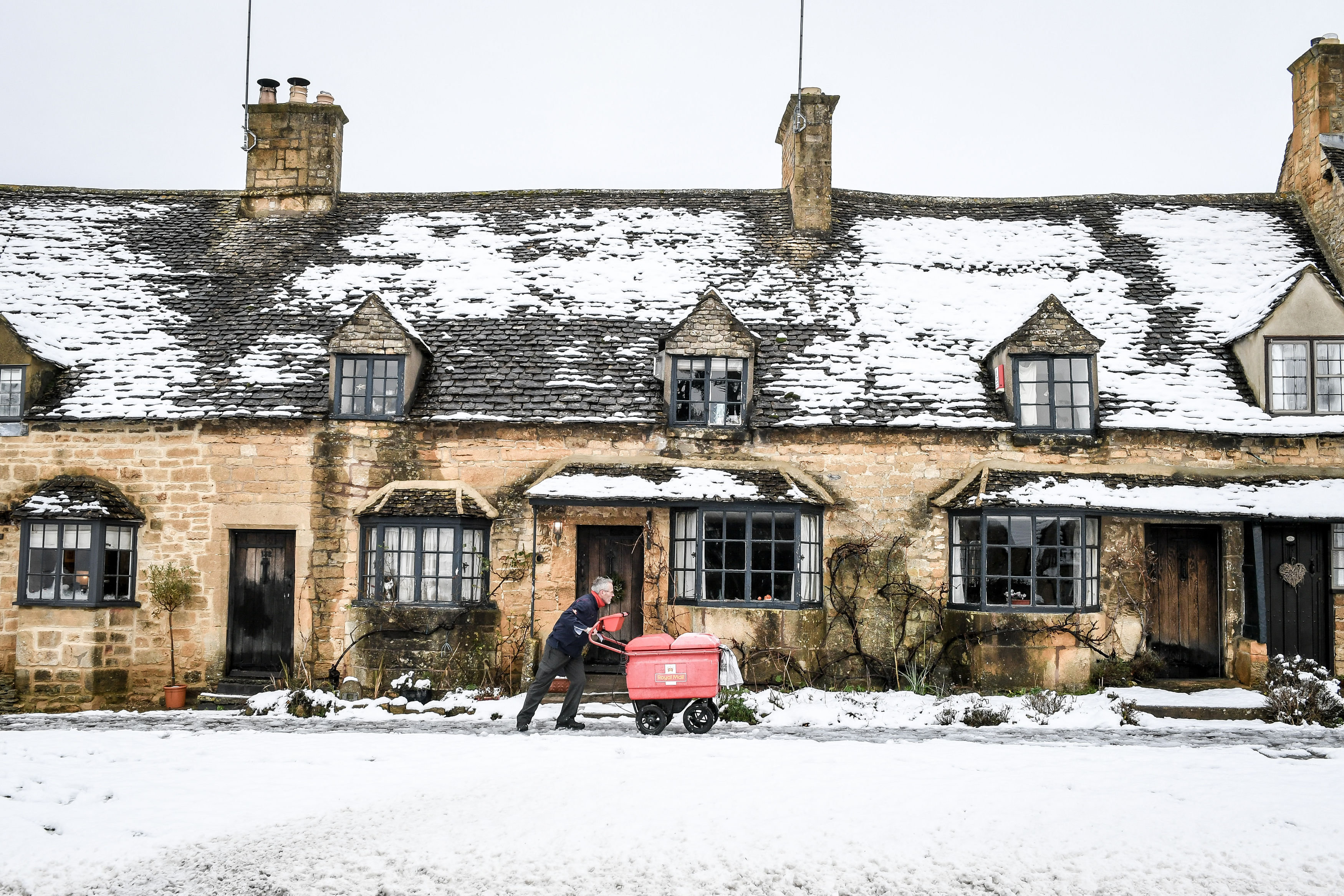 <strong>A postman pushes his trolley past snow-covered cottages on the High Street in Broadway, Worcestershire&nbsp;</strong>