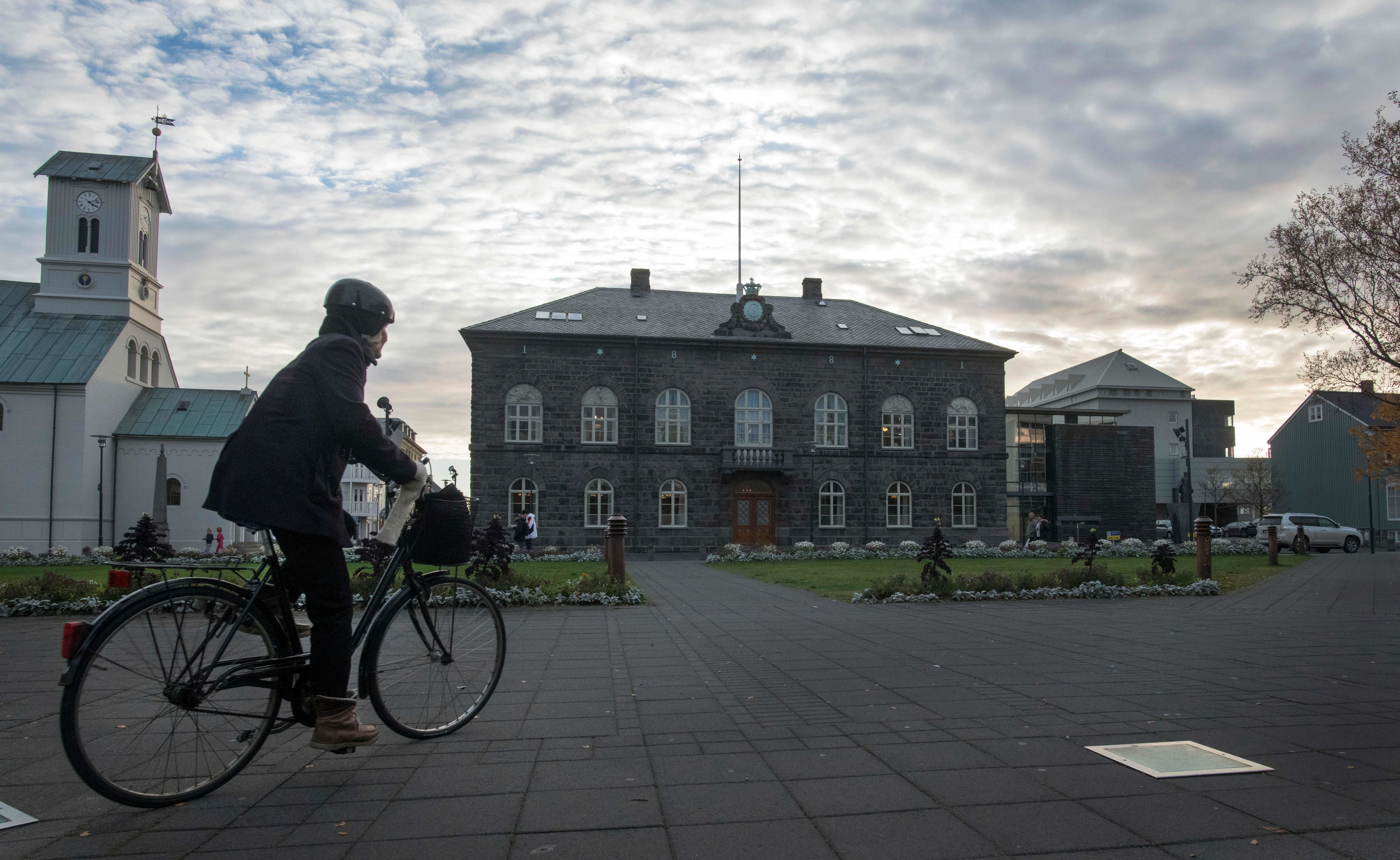 <strong>A woman cycles past the Althingi Parliament building in Reykjavik, Iceland&nbsp;</strong>