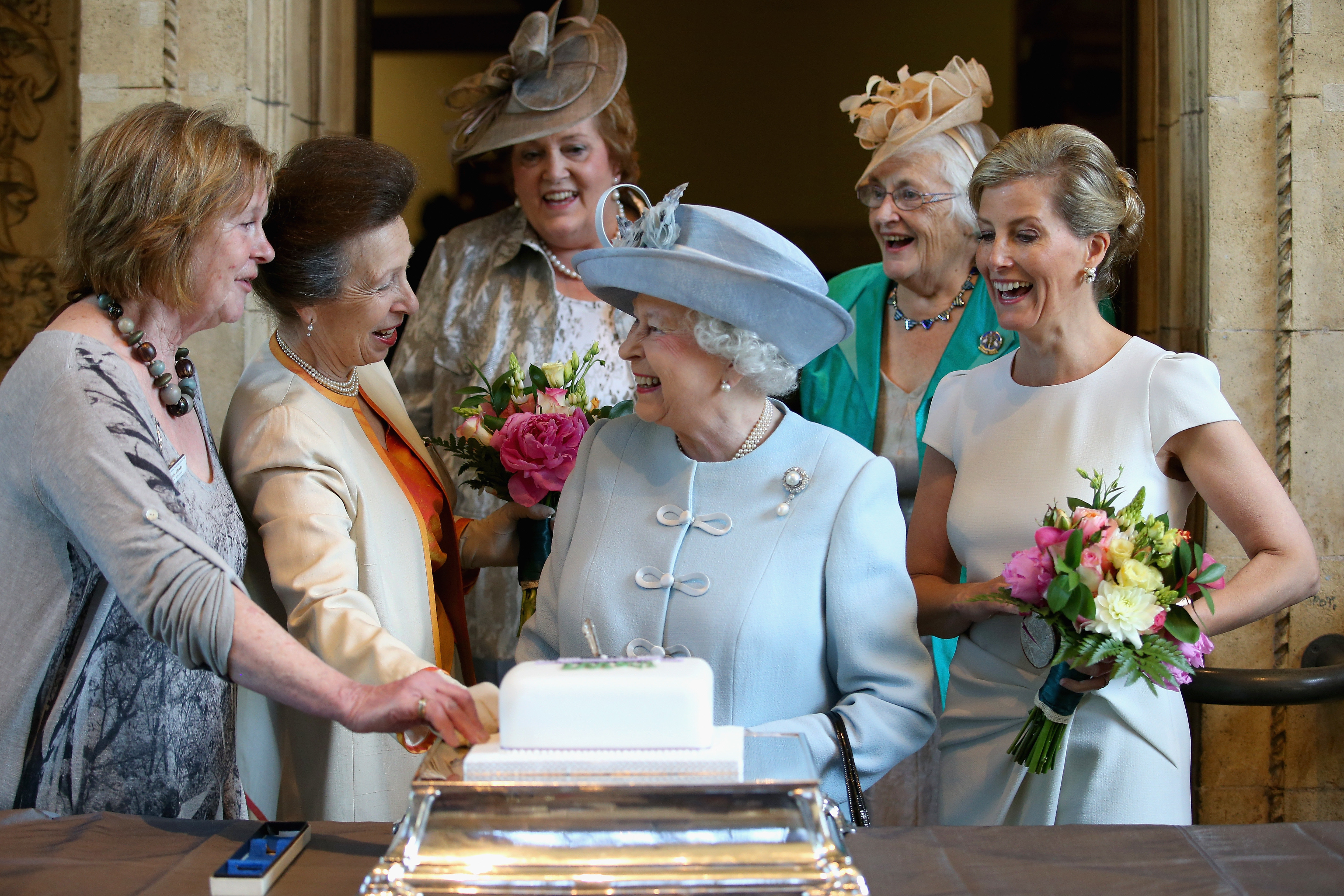 'This is what I call an unscripted moment... You can see she's just having a laugh'. Sophie, Countess of Wessex and Prince Anne look on as the Queen cuts a Women's Institute Celebrating 100 Years cake at its centenary.