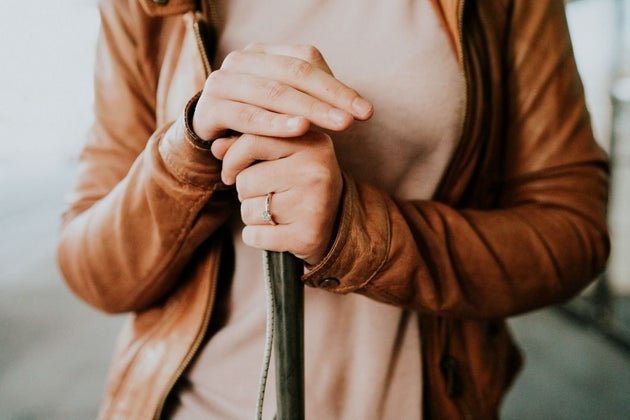 Agnew is shown in a close-up with her right hand atop her cane with her left hand, adorned with her engagement ring, below it.