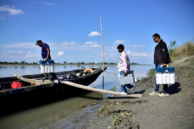 Election staff carrying Voter Verifiable Paper Audit Trail machines and an Electronic Voting Machine (EVM) board a boat to reach remote polling stations at Lahori Chapori in Golaghat district in the northeastern state of Assam.