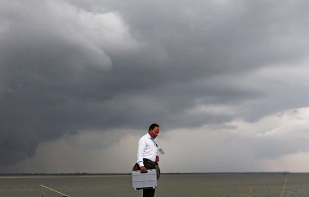 A polling officer carrying an electronic voting machinewalks toward his vehicle after arriving on a ferryboat in Nimatighat, Jorhat district, in the northeastern Indian state of Assam