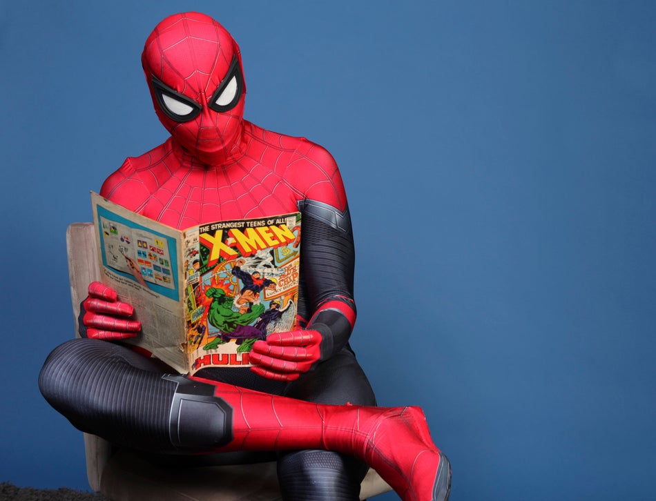 Evan Nuzum reads a comic book dressed as Spider-Man.