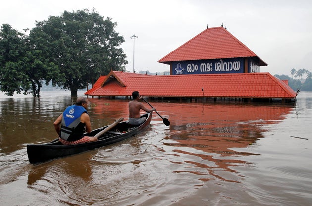 Members of a rescue team row a boat towards a submerged temple to look for a man believed to be stranded inside the temple during heavy rains on the outskirts of Kochi in Kerala, August 8, 2019.