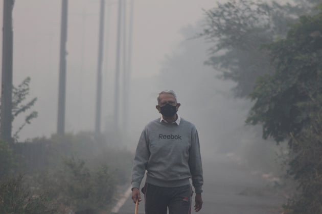 NEW DELHI, INDIA - 2019/11/15: A man wearing a protective mask jogs on a foggy morning in Noida on the outskirts of New Delhi.
