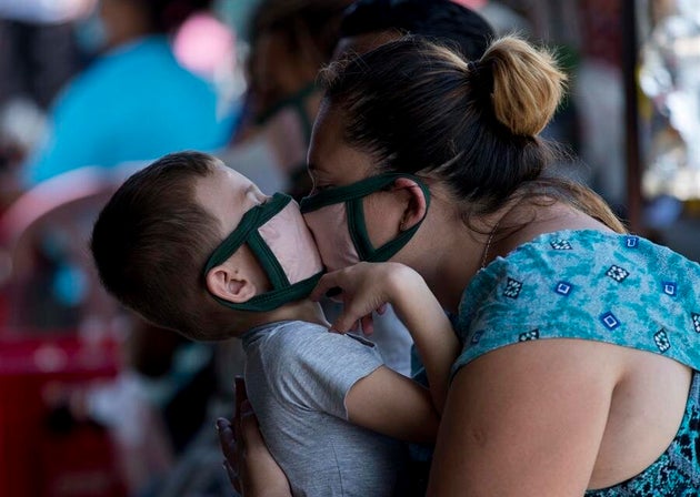 Una mujer besa a su hijo con mascarilla.