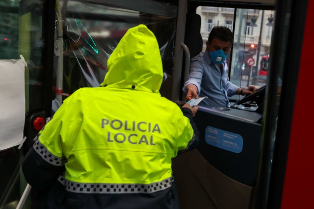 Un policía local entrega una mascarilla a un conductor de autobús en Valencia.