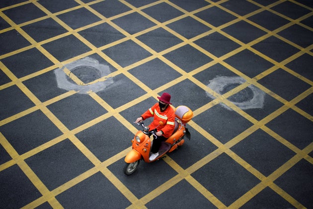 A woman wearing a face mask rides a scooter on a street in Wuhan, Hubei province, April 6, 2020.
