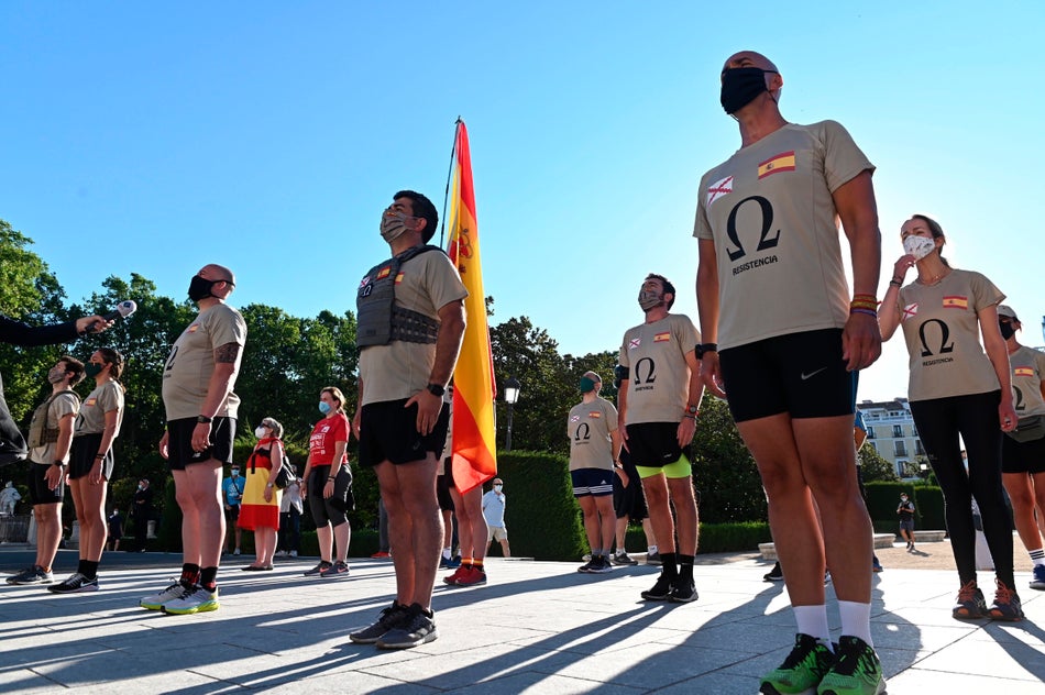 Un grupo de personas cantan el himno de la Legión en las inmediaciones del Patio de la Armería del Palacio Real en Madrid este jueves donde se celebra la ceremonia civil en la que se rinde tributo a los casi 30.000 fallecidos a consecuencia de la COVID-19 en España.