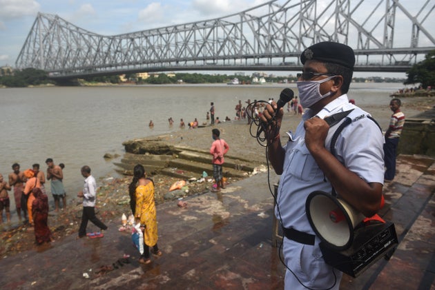 A police officials issues warnings for devotees performing rituals on the bank of river Hooghly to mark the occasion of Mahalaya, at Jagannath Ghat, near Howrah Bridge on September 17, 2020 in Kolkata, India.