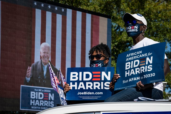 Trump And Biden Each Go On Offense In States They're Trying To Flip - Supporters listen while sitting atop their car as Democratic presidential nominee Joe Biden speaks during a drive-in campaign