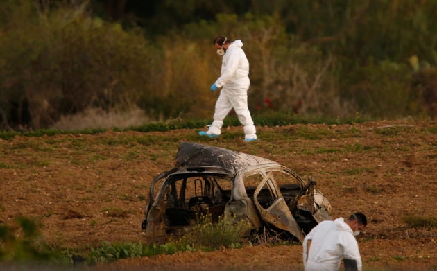 Forensic experts walk in a field after a powerful bomb blew up a car and killed investigative journalist Daphne Caruana Galizia in Bidnija, Malta.