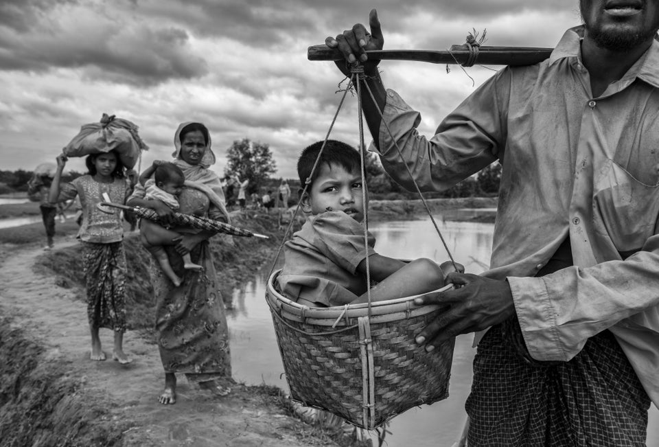 A Rohingya refugee boy is carried in a basket by a relative on Sept. 24 after crossing the border on the Bangladesh side of the Naf River while fleeing Myanmar.