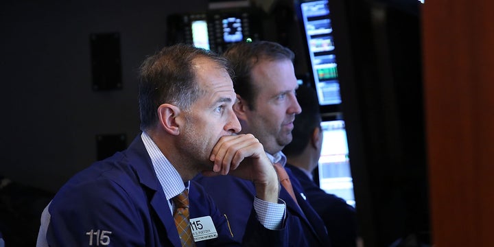 Traders work on the floor of the New York Stock Exchange (NYSE) a day after the market closed for over three hours yesterday