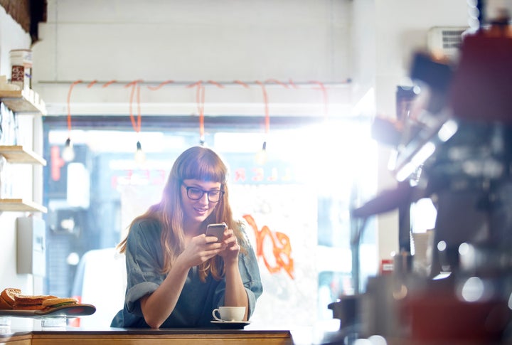 Girl relaxes with coffee while checking her phone