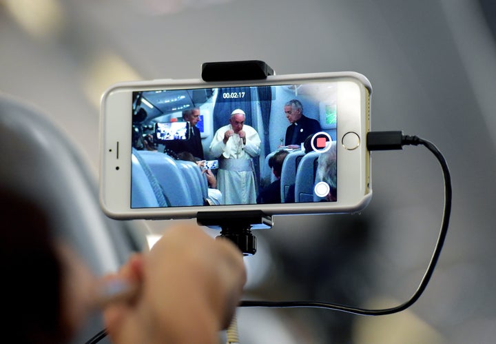 A journalist takes with his mobile phone a picture of Pope Francis during a press conference on July 13, 2015, onboard a plan