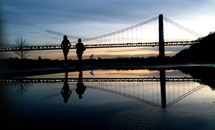 FILE - In this Nov. 26, 2011 file photo two women walk at Palisades Interstate Park as the sun sets over the George Washington Bridge, in Fort Lee, N.J. Many people have known little about Fort Lee until a political scandal centering on New Jersey Gov. Chris Christie enveloped the borough. Now for residents of the New York City bedroom community defined by both a feisty pride and frustration over the mixed blessings of proximity to the George Washington Bridge, the scandal is the reminder they did not need of how the bridge dictates the rhythm of everyday life. (AP Photo/Julio Cortez, File)