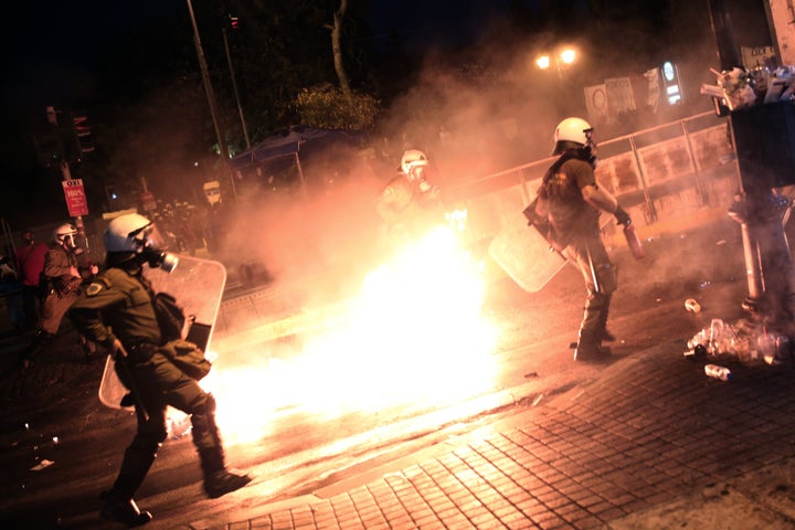 Riot policemen run after protesters throwing petrol bombs in central Athens, during an anti-austerity protest on July 15, 2015. Anti-austerity protesters hurled petrol bombs at police in front of Greece's parliament on July 15 as lawmakers began debating unpopular reforms needed to unlock a new eurozone bailout. Riot police responded with tear gas against dozens of hooded protesters who set ablaze parts of Syntagma square in central Athens AFP PHOTO / ANGELOS TZORTZINIS (Photo credit should read ANGELOS TZORTZINIS/AFP/Getty Images)