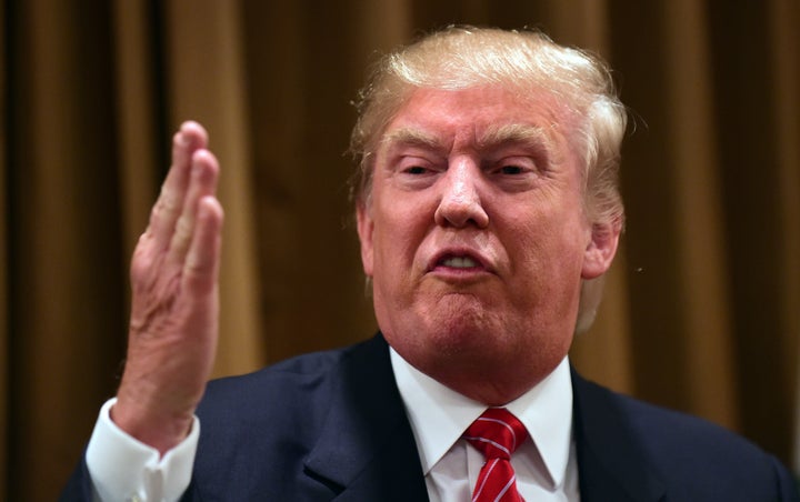 Donald Trump gestures while speaking surrounded by people whose families were victims of illegal immigrants on July 10, 2015