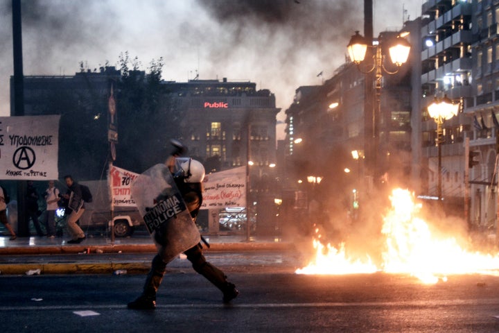 ATHENS, GREECE - JULY 15: Riot police use teargas in front of the Greek Parliament on July 15, 2015 in Athens, Greece. Anti-austerity protesters hurled petrol bombs at police in front of Greece's parliament as lawmakers began debating deeply unpopular reforms needed to unlock a new eurozone bailout. Riot police responded with tear gas against dozens of hooded protesters who set ablaze parts of Syntagma square in central Athens. (Photo by Milos Bicanski/Getty Images)