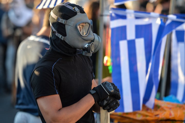 A protester wearing a gas mask attends an anti-austerity protest outside the Greek parliament in Athens on July 15, 2015. Greek lawmakers backed a deeply contentious bailout package, clearing the first hurdle towards securing a rescue hours before fresh talks between eurozone ministers but leaving the radical left government in Athens weakened. AFP PHOTO / ANDREAS SOLARO (Photo credit should read ANDREAS SOLARO/AFP/Getty Images)