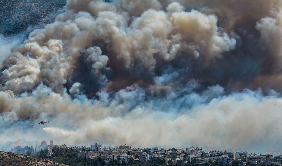 An airplane flies over smoke billowing over Athens, on July 17. 