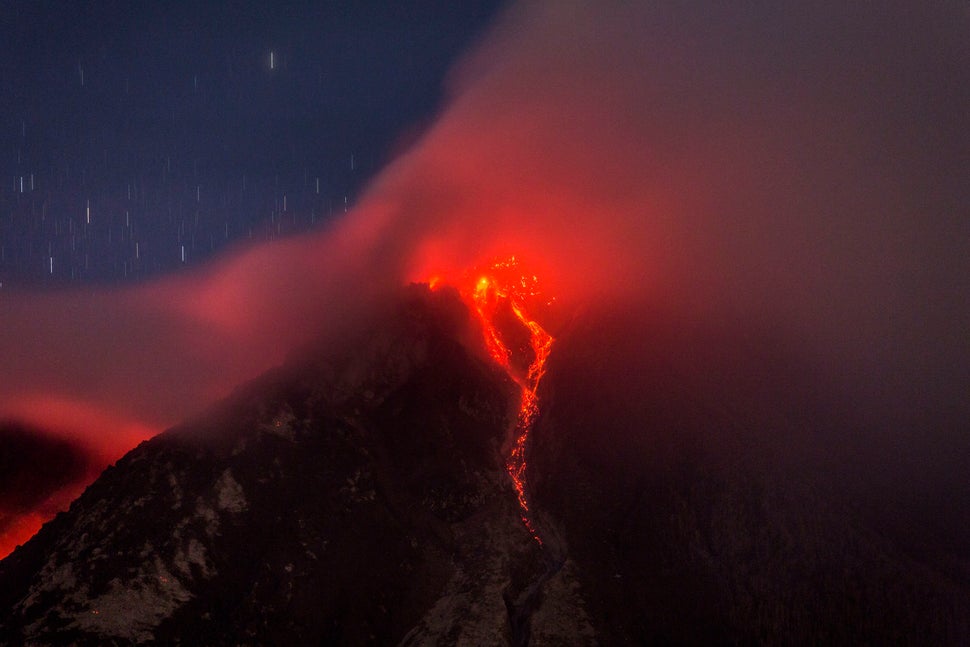 KARO, NORTH SUMATRA, INDONESIA - JUNE 18: Hot lava runs down Mount Sinabung, seen from Tiga Kicat village on June 18, 2015 in Karo district, North Sumatra, Indonesia. According to The National Disaster Mitigation Agency, more than 10,000 villagers have fled their homes since the authorities raised the alert status of Mount Sinabung erupting to the highest level. (Photo by Ulet Ifansasti/Getty Images)