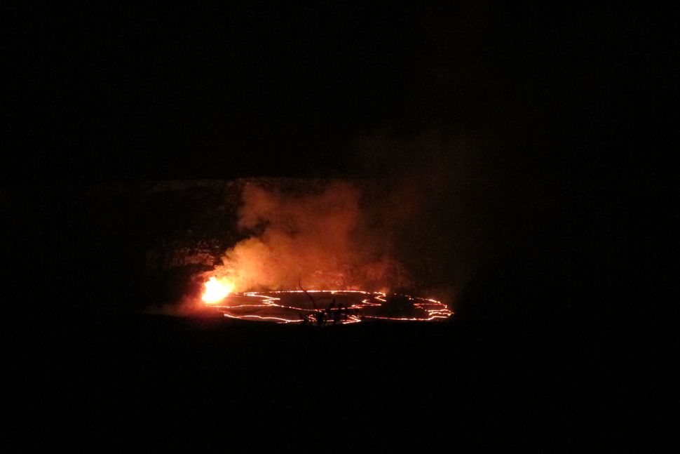 In this Saturday, May 9, 2015 photo, molten rock lights up the night as it spews into a lake of lava near the summit of Kilauea volcano on Hawaii's Big Island. The lava lake had reached a record high level on May 8 and then began descending, making scientists wonder where the molten rock will go next. (AP Photo/Cathy Bussewitz)