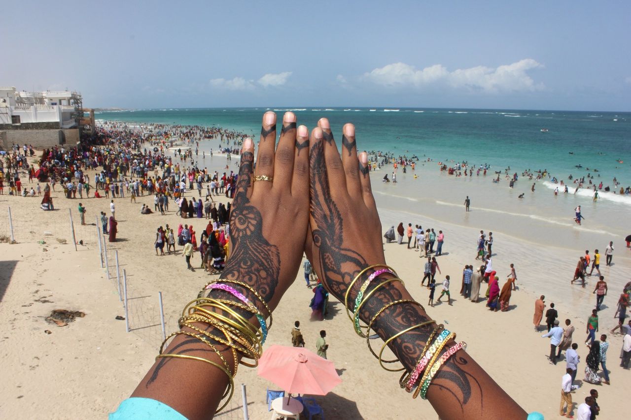 <p>A young woman displays her henna tattoo over a view of Liido Beach.</p>