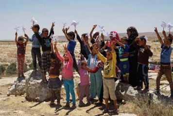 Palestinian children in Susiya hold up their handmade pinwheels for peace on June 23, 2015. They wrote what peace meant