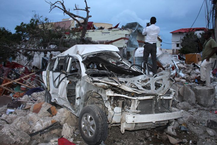 A man stands over the rubble next to a destroyed car near the damaged Jazeera Palace hotel following a suicide attack in Mogadishu on July 26, 2015. 