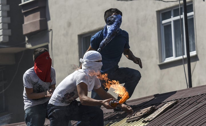 Left-wing protesters prepare to throw a Molotov cocktail from a rooftop during clashes with Turkish police officers on July 26, 2015, at Gazi district in Istanbul.