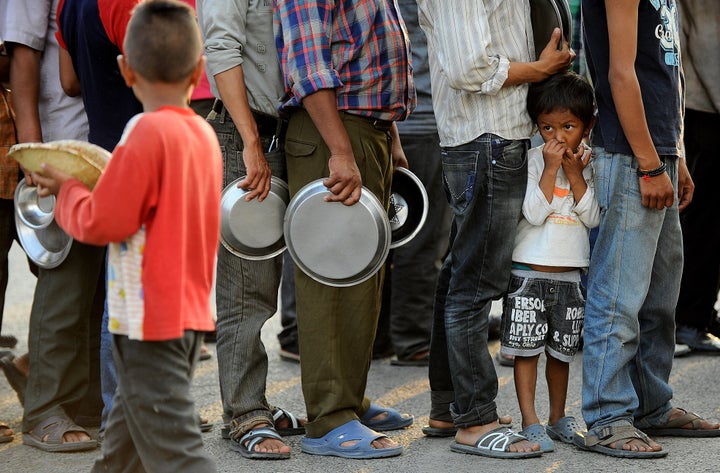 Nepalese people queue to receive food and goods at a relief camp for survivors of the Nepal earthquake in Kathmandu on May 19, 2015.