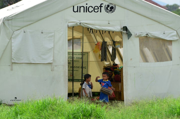 In this photograph taken on July 23, 2015, Nepalese children play with a drum at a relief camp for earthquake survivors in Ka