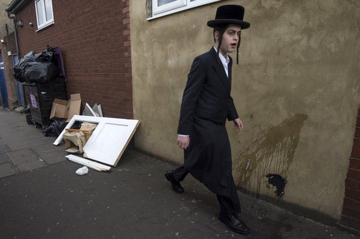 An Orthodox Jewish man walks past a damaged door belonging to the Ahavas Torah synagogue in the Stamford Hill following a suspected anti-Semitic incident.