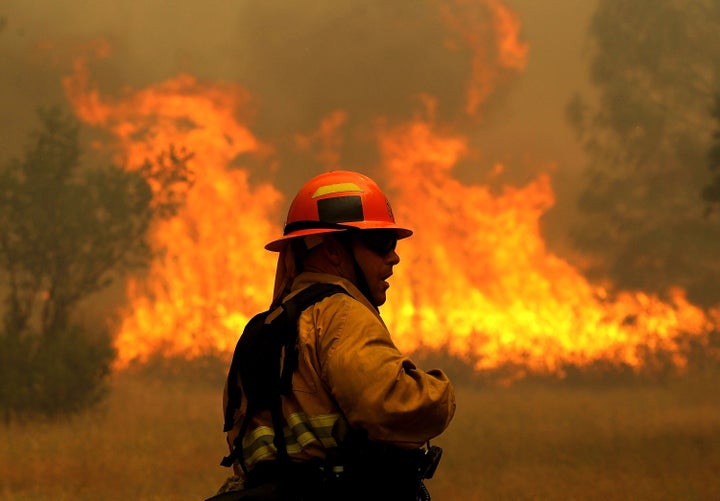 A firefighter monitors flames from the Rocky Fire as it approaches a home on July 31, 2015 in Lower Lake, California.