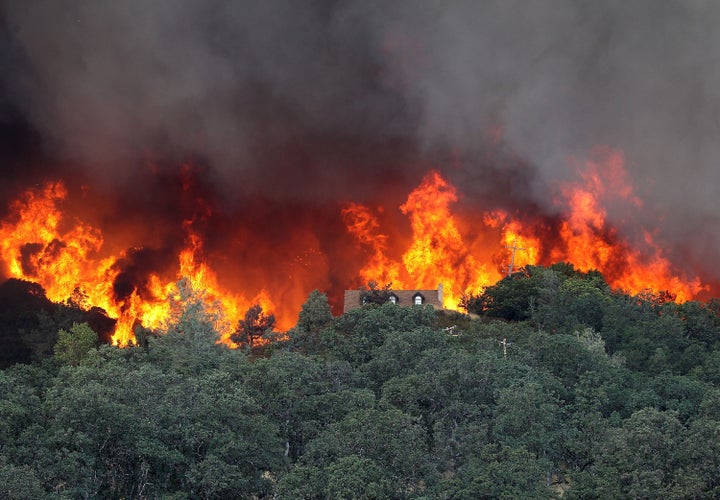 <span>Flames from the Rocky Fire approach a house on July 31, 2015 in Lower Lake, California. Over 900 firefighters are battl