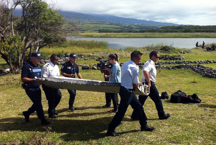 <span>Police carry a piece of debris from an unidentified aircraft found in the coastal area of Saint-Andre de la Reunion, in