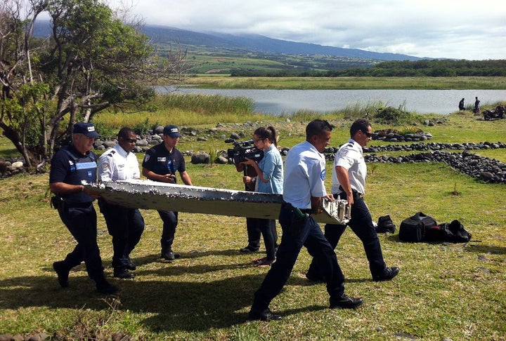 Police carry a piece of debris from an unidentified aircraft found in the coastal area of Saint-Andre de la Reunion, in the east of the French Indian Ocean island of La Reunion, on July 29, 2015. 