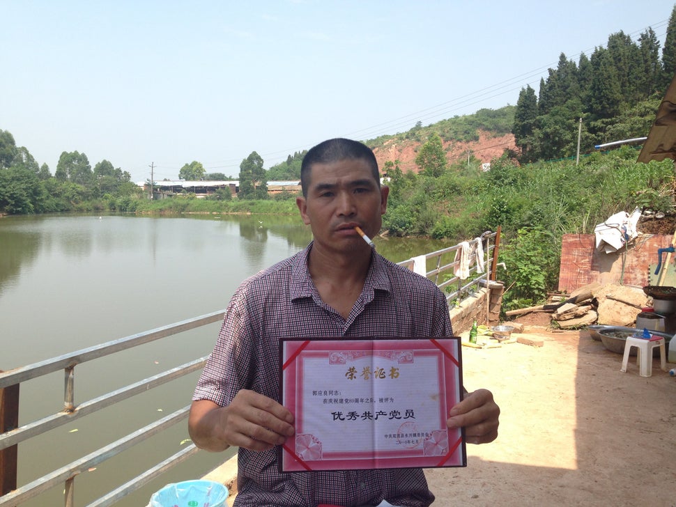 Guo Yingliang, a farmer who has protested over compensation on his seized farmland, holds up a certificate commending him as