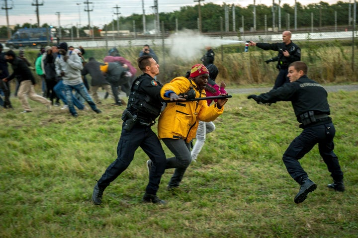 French gendarmes try to stop migrants on the Eurotunnel site in Coquelles near Calais, northern France, on late July 29, 2015. 