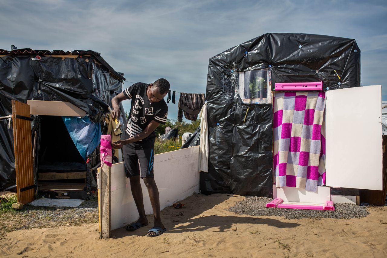 Muher from Sudan adds a dividing wall outside his tent in a makeshift camp near the port of Calais on Aug. 1, 2015.